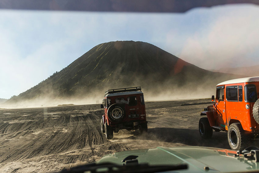 Jalur Bromo Ditutup Sementara, jeep wisata melintas di lautan pasir Gunung Bromo dengan latar pegunungan — sumber foto googleusercontent.com