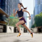 Wanita berlari mengenakan Running Shoes Wanita Terbaik 2025 Puma Fast-R Nitro Elite 3 berwarna kuning hitam dengan pakaian olahraga ungu di area perkotaan — sumber foto id.puma.com