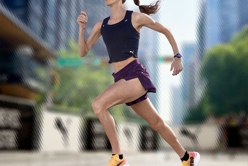Wanita berlari mengenakan Running Shoes Wanita Terbaik 2025 Puma Fast-R Nitro Elite 3 berwarna kuning hitam dengan pakaian olahraga ungu di area perkotaan — sumber foto id.puma.com