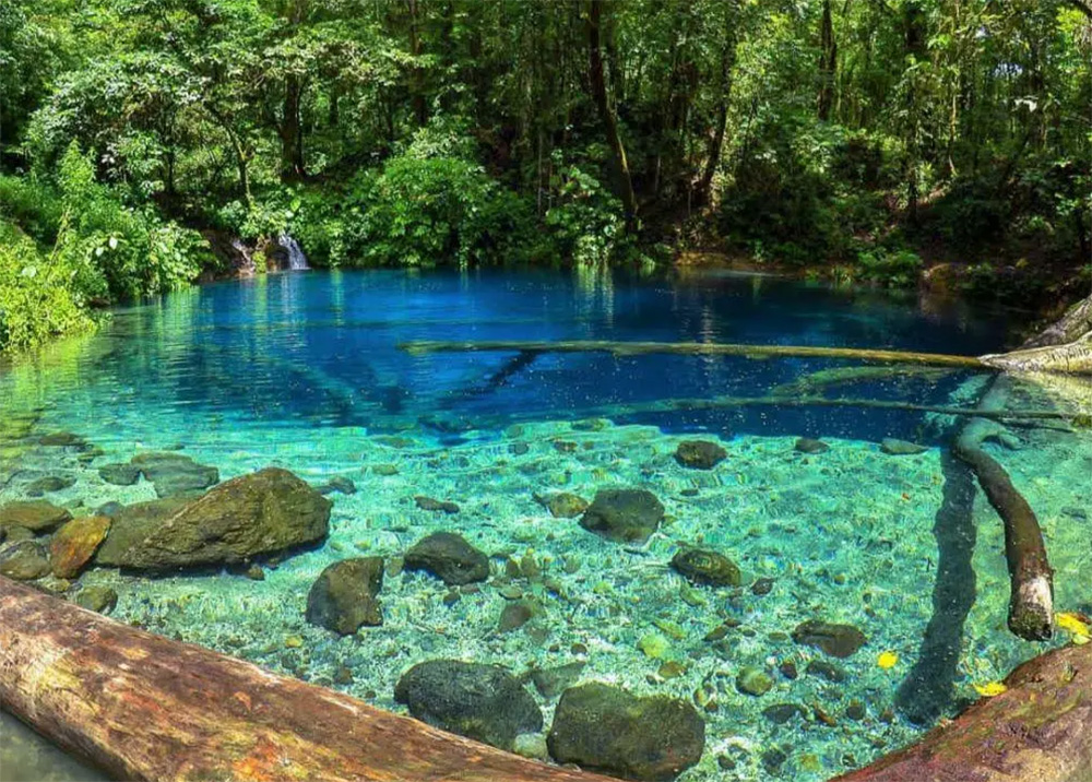 Pesona Danau Kaco dengan air berwarna biru jernih di tengah hutan hijau, suasana alami yang tenang dan memukau di Lempur, Kerinci.