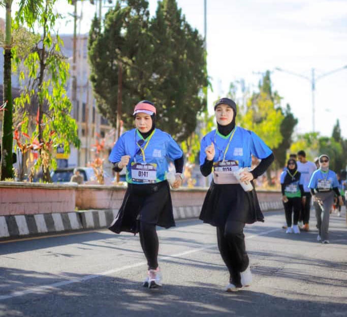 "Peserta lari perempuan berlari bersama di jalan, menggambarkan momen seru running fomo.