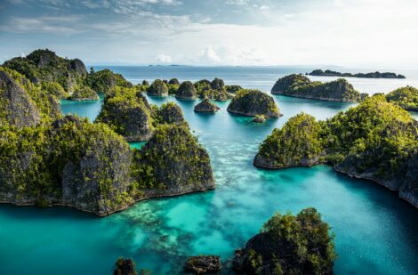 Pemandangan gugusan pulau karst hijau di atas laut biru jernih yang menakjubkan, ikon wisata Raja Ampat di Papua Barat